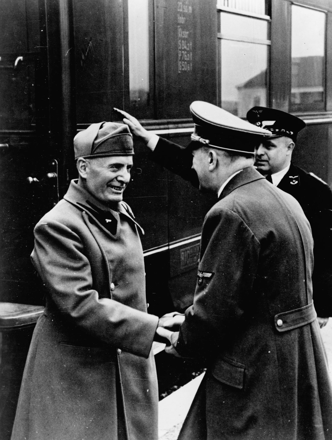 Adolf Hitler greets Benito Mussolini as he arrives at the train station before their meeting at Schloss Kleßheim 